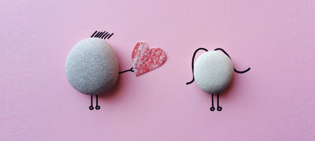 Trabajo manual con piedras simulando una escena romántica sobre fondo rosa 