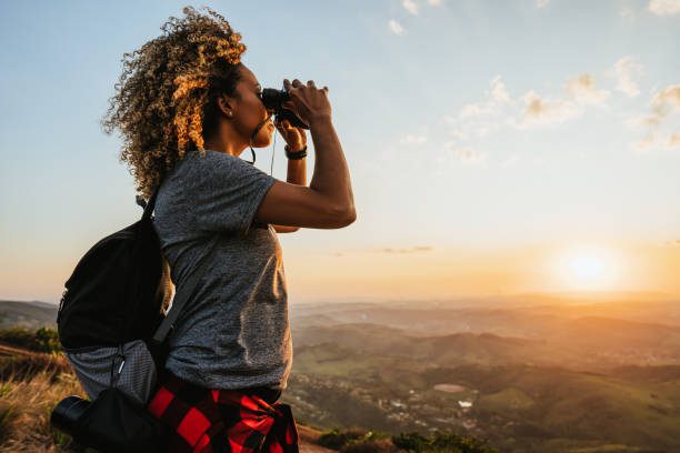 Mujer observando el paisaje con prismáticos desde una montaña en Madrid