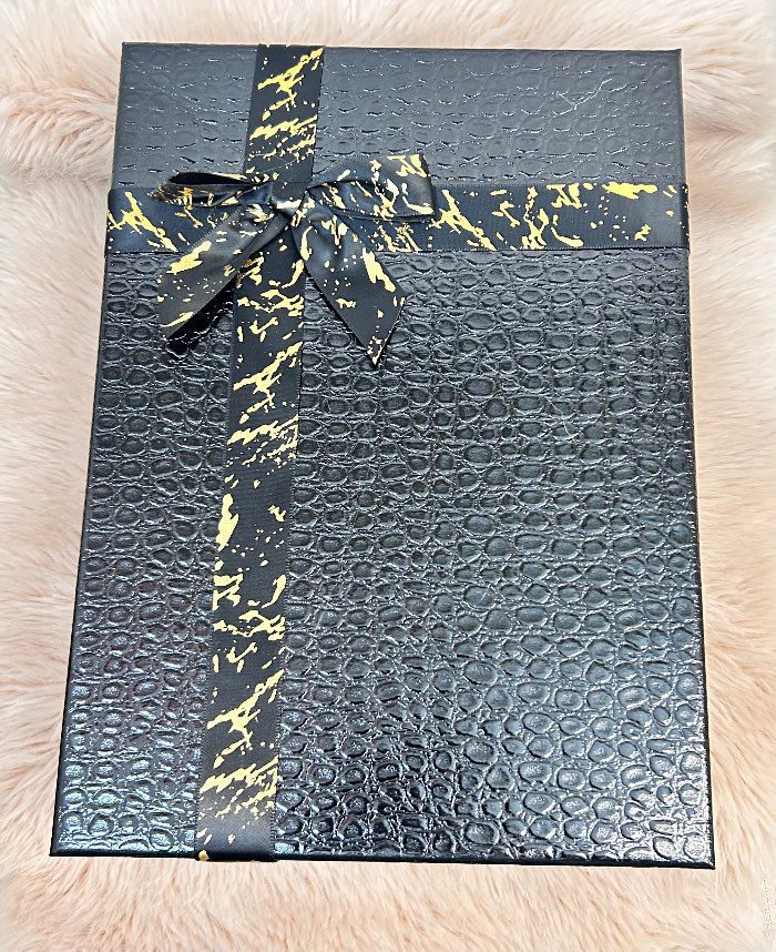Caja de regalo con textura de piel de cocodrilo y lazo negro con detalles dorados