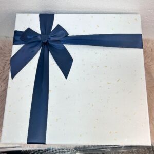 Caja de regalo elegante blanca con lazo azul marino y detalles dorados
