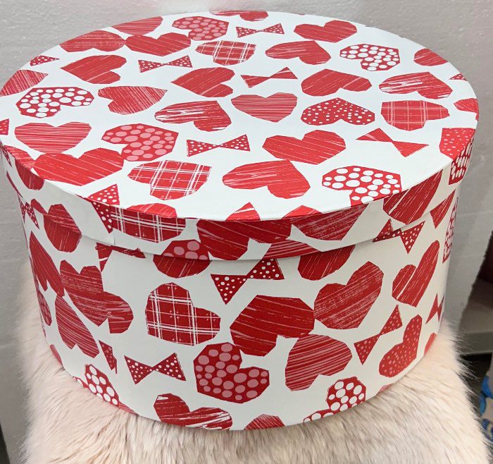 Caja de regalo redonda con diseño de corazones y lazos rojos