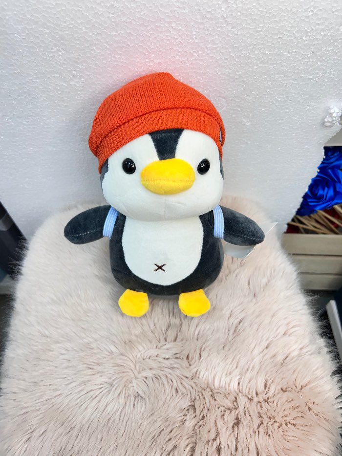 Peluche de pingüino con gorra naranja