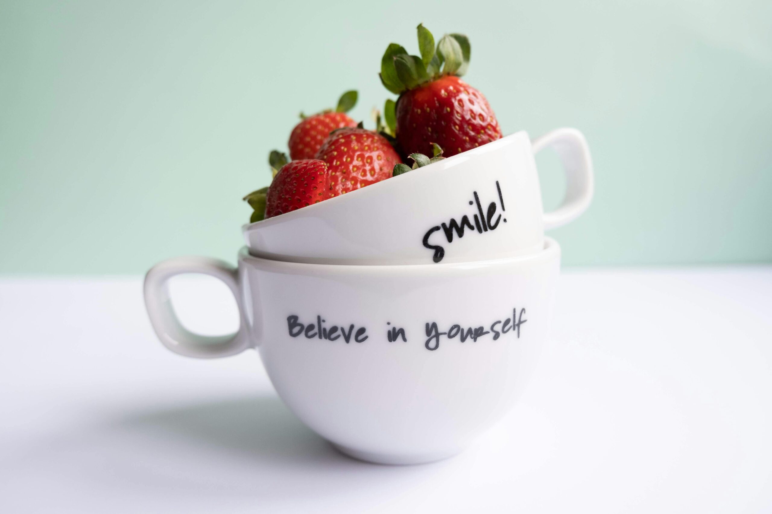 Two cups with strawberries and positive messages, perfect for food and lifestyle themes.