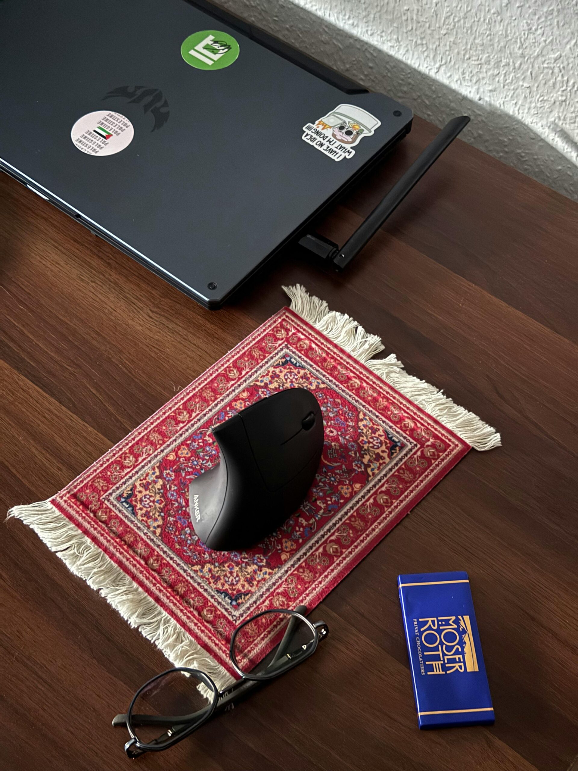 Stylish desk setup with a laptop, mouse on decorative rug, and accessories.