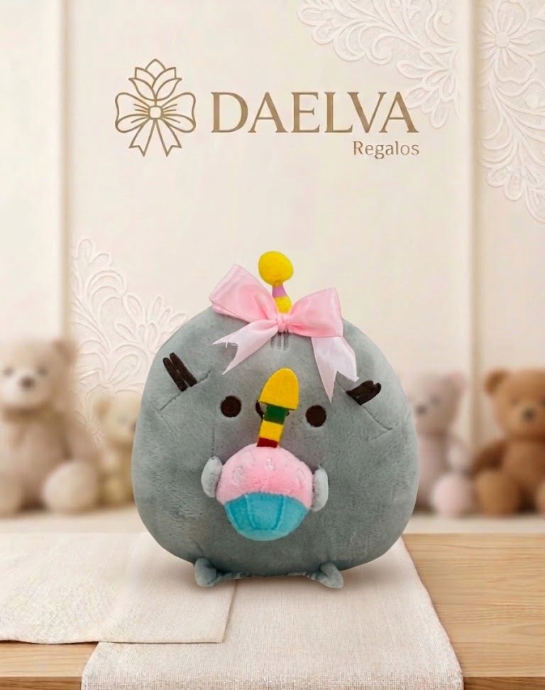 Gatito de peluche gris y redondo con lazo rosa que sostiene un cupcake azul con una vela amarilla
