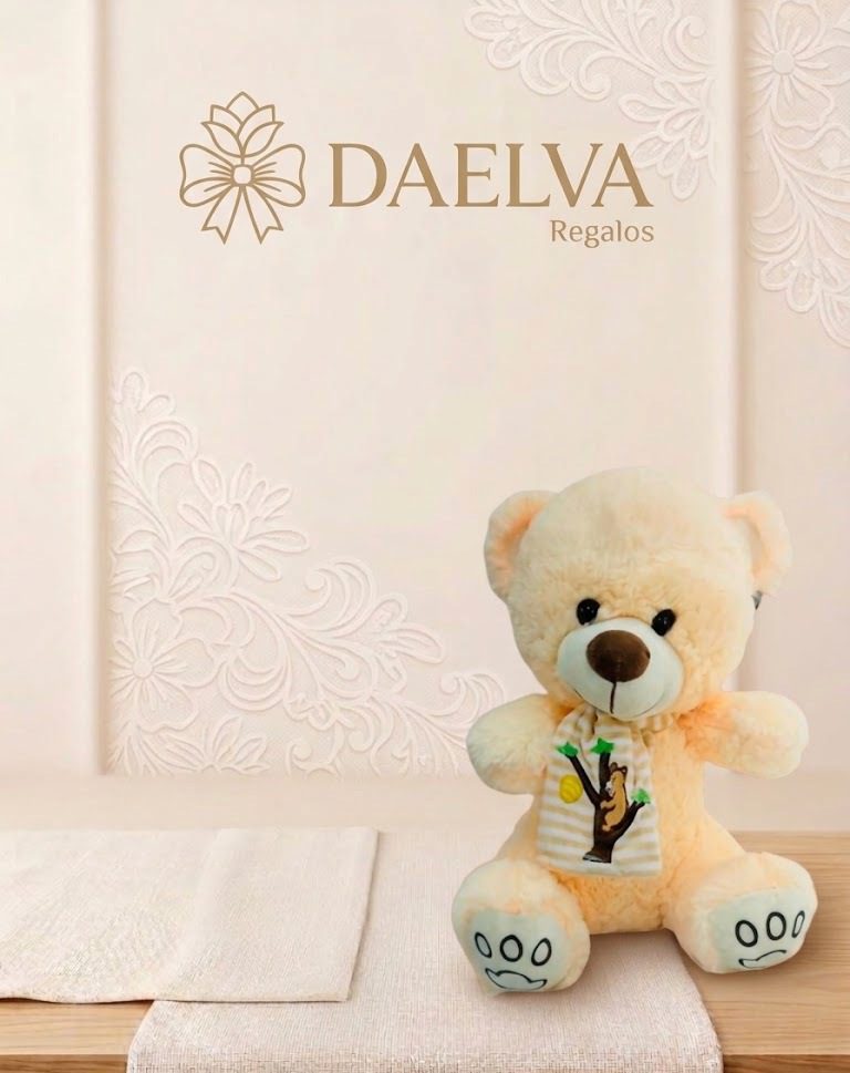 Osito de peluche crema sentado con un babero blanco con dibujo de un árbol y nariz marrón