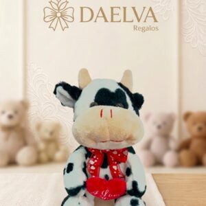 Peluche de vaca blanca y negra con un lazo rojo de corazones y un corazón rojo entre las patas